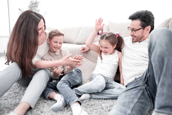 Ouders spelen met kinderen zittend op het tapijt in de woonkamer — Stockfoto