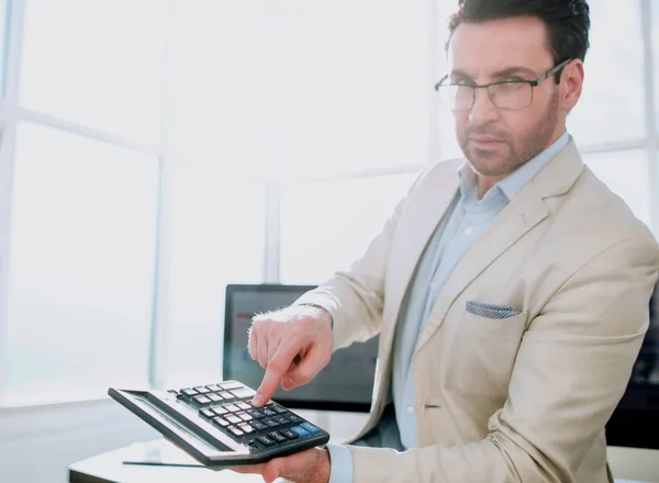 Homem de negócios confiante apontando para calculadora — Fotografia de Stock