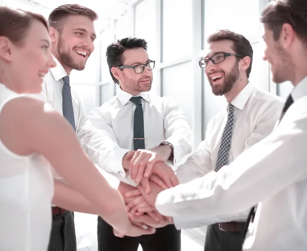 Close up.a equipe de negócios sorrindo fica com as mãos dobradas juntas. — Fotografia de Stock