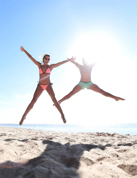 Zdjęcie szczęśliwej pary skaczącej po plaży. — Zdjęcie stockowe