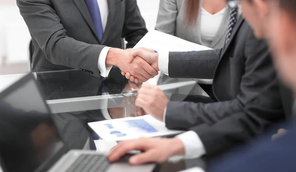 Zwei Geschäftsleute schütteln Kollegen im Hintergrund die Hand. — Stockfoto