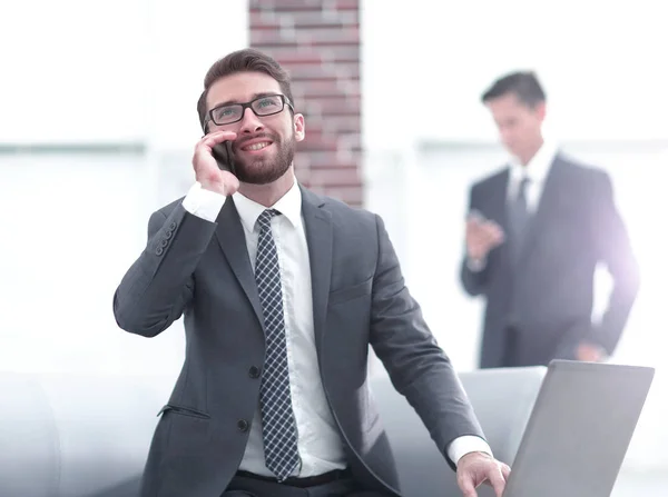 Pewny siebie młody człowiek rozmawiający przez telefon w biurze — Zdjęcie stockowe