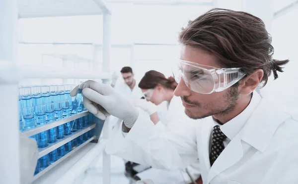 Assistente de laboratório em óculos e jaleco com tubo de ensaio — Fotografia de Stock