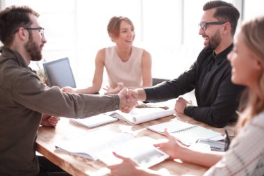 gülümseyen iş ortakları bir iş toplantısında el sıkışıyor.