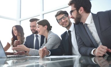 İş ekibi ofisteki masada oturuyor.