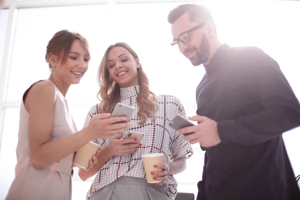 Equipe de negócios olhando para as telas de seus smartphones — Fotografia de Stock