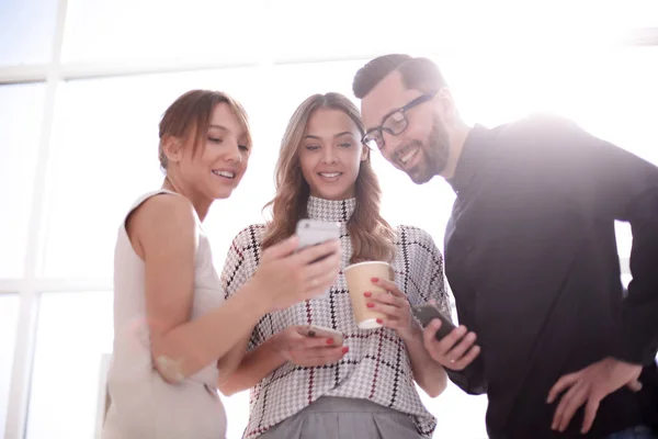 Equipe de negócios olhando para as telas de seus smartphones — Fotografia de Stock