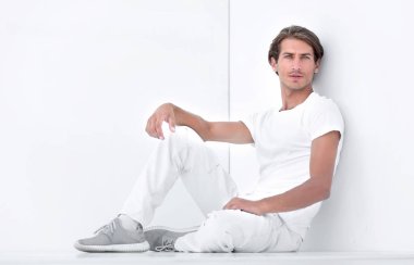 Beyaz bir duvar oturan üzgün genç adam