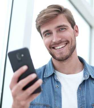 yakın kapatın. genç adam akıllı telefonunda e-posta okuma.