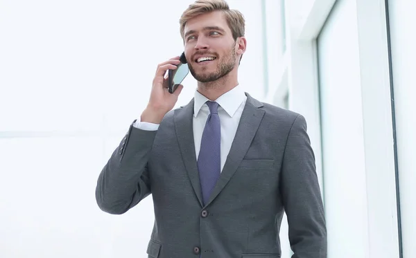 站在办公室窗户附近的一部手机上说话的商人 — 图库照片