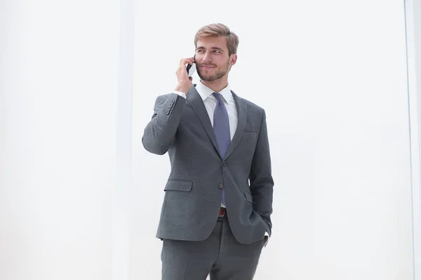 Homme d'affaires parlant sur un téléphone portable debout près de la fenêtre du bureau — Photo