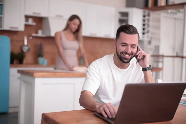 Jovem falando no smartphone na cozinha doméstica — Fotografia de Stock