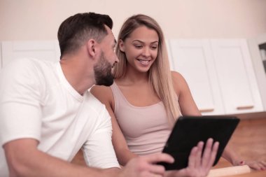 Genç çift ev mutfağında tablet ile web sörf