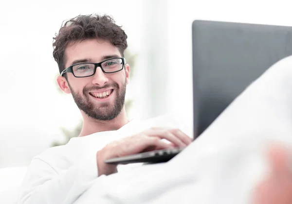 Sorrindo homem usando laptop deitado na cama — Fotografia de Stock