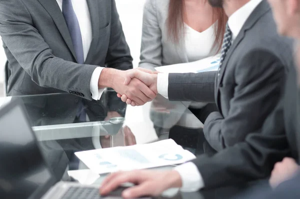 Two businessmen shaking hands with colleagues on background. — Stock Photo, Image