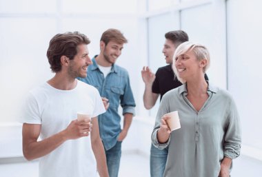 ofis koridorundan geçen kahve bardakları ile çalışanlar
