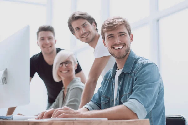 Sonriente joven de pie cerca de la oficina Escritorio — Foto de Stock