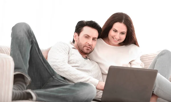 Ευτυχισμένο ζευγάρι που κάθεται στον καναπέ στην αγκαλιά της, ψάχνει στο φορητό υπολογιστή — Φωτογραφία Αρχείου