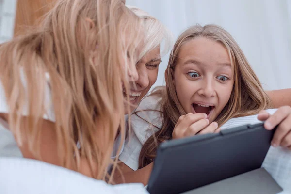 Mamma med sina små flickor tittar på videor som ligger på sängen — Stockfoto