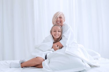 anne ve küçük kızı sabah erken saatlerde yatakta oturuyor.