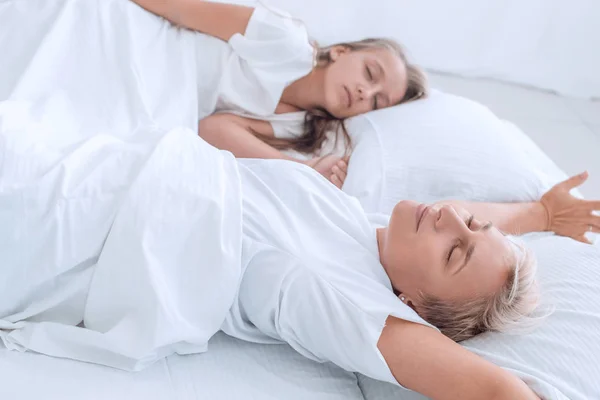 Mutter mit ihrer kleinen Tochter frühmorgens auf dem Bett liegend — Stockfoto