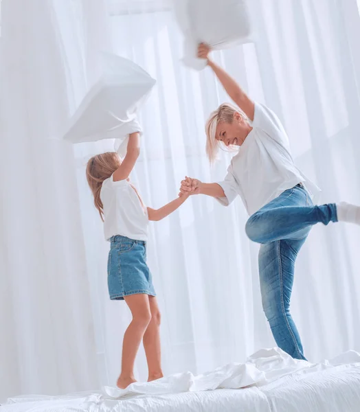 close up. mom and daughter have a pillow fight on the bed
