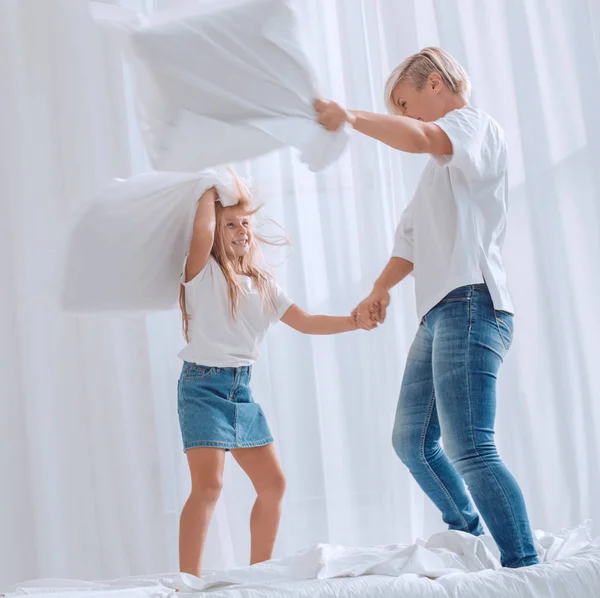 De cerca. mamá y su hija tienen una pelea de almohadas en la cama —  Fotos de Stock