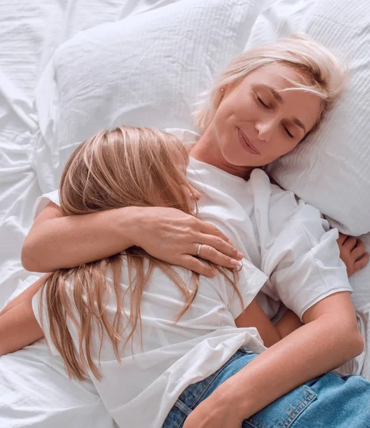 Mãe feliz falando com sua filha deitada na cama . — Fotografia de Stock