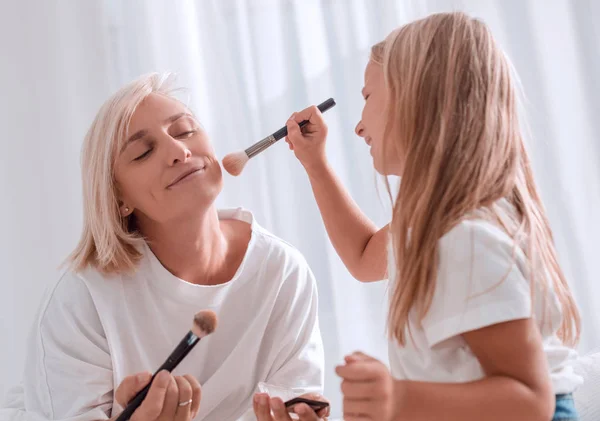 Madre e hija joven jugando y aplicando maquillaje juntas — Foto de Stock