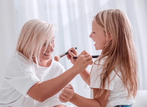 Madre e hija joven jugando y aplicando maquillaje juntas — Foto de Stock
