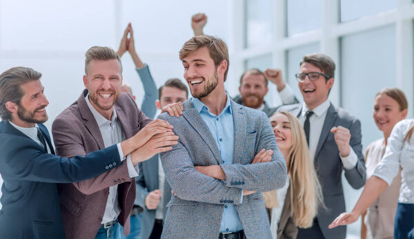 Закрывай. веселые сотрудники компании аплодируют коллеге
.