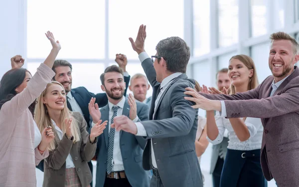 group of cheerful company employees congratulating their colleague