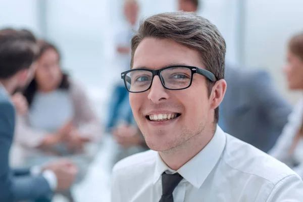 Κοντά. χαμογελαστός νέος επιχειρηματίας στο παρασκήνιο του γραφείου. — Φωτογραφία Αρχείου