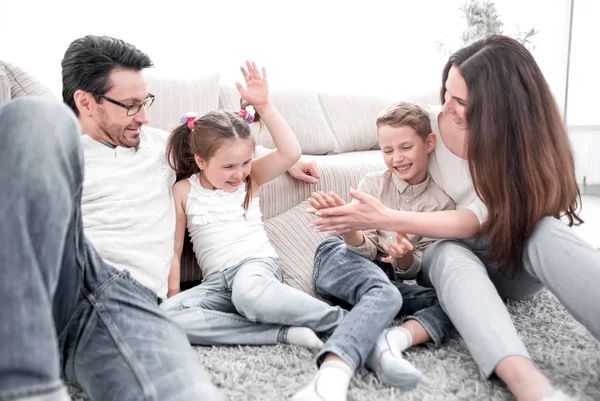 parents play with children sitting on the carpet in the living room