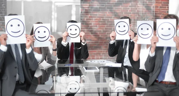 Business team keeps smiley icons sitting at the Desk Stock Photo