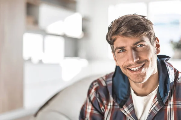 Jonge man zittend in een stoel in zijn gezellige appartement — Stockfoto