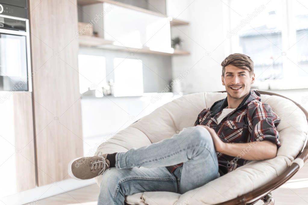 smiling man sitting in a comfortable chair in his apartment