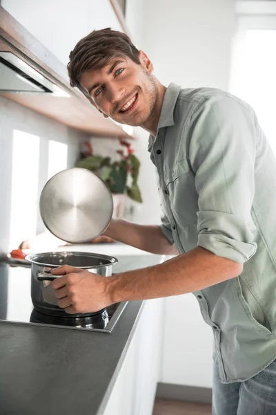 Fecha. um homem sorrindo olha em uma panela de comida — Fotografia de Stock