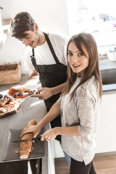 Jovem mulher e seu namorado estão fazendo sanduíches na cozinha — Fotografia de Stock