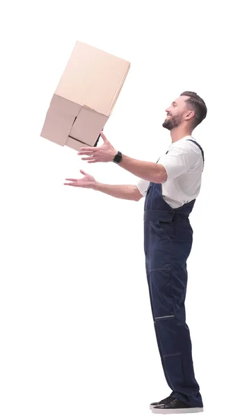 Seitenansicht. Lächelnder Mann in Overalls fängt einen Karton — Stockfoto