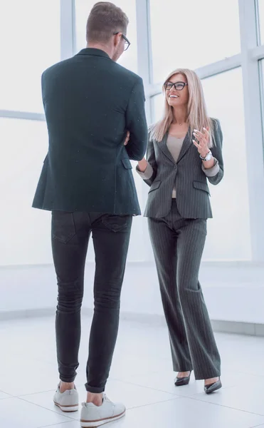 smiling employees discuss something standing in the office corridor