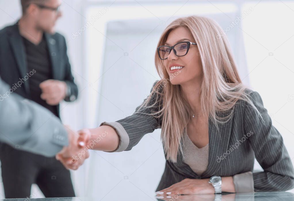 close up. business woman shaking hands sitting behind a Desk.