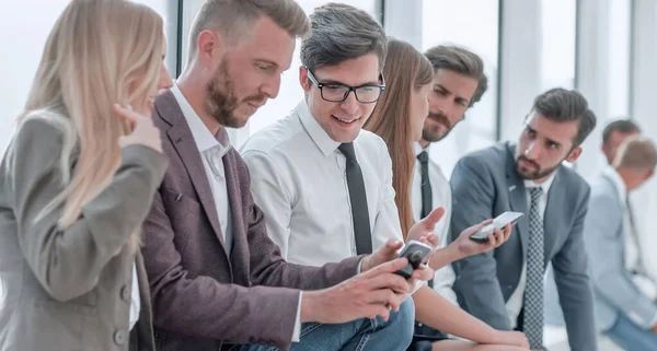 Young employees using their smartphones to view the news online — ストック写真