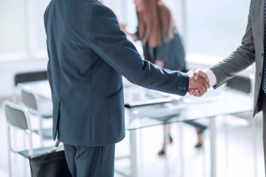 Ofisin arka planında iş adamlarının el sıkışması