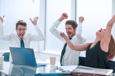 Ofis masasında oturan mutlu iş ekibi.