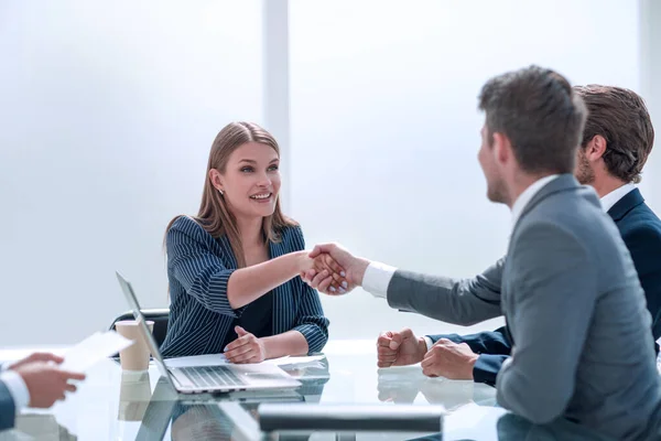 Hombre de negocios estrechando la mano con la mujer de negocios sentada en la mesa de negociaciones — Foto de Stock