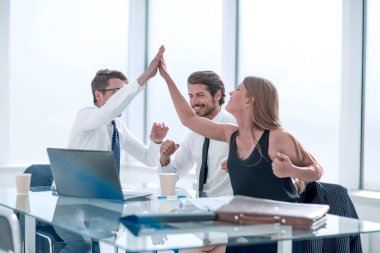 Ofis masasında oturan mutlu iş ekibi.