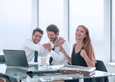 Ofis masasında oturan mutlu iş ekibi.