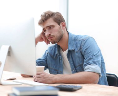 onun bilgisayar monitörü bakarak bir kahve Fincan ı ile üzgün işadamı