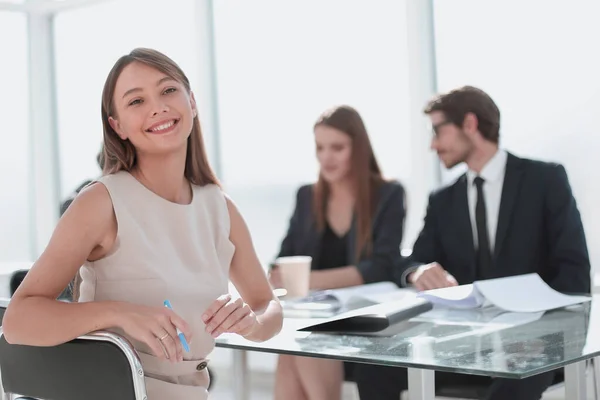 坐在办公室桌旁的微笑的女商人 — 图库照片